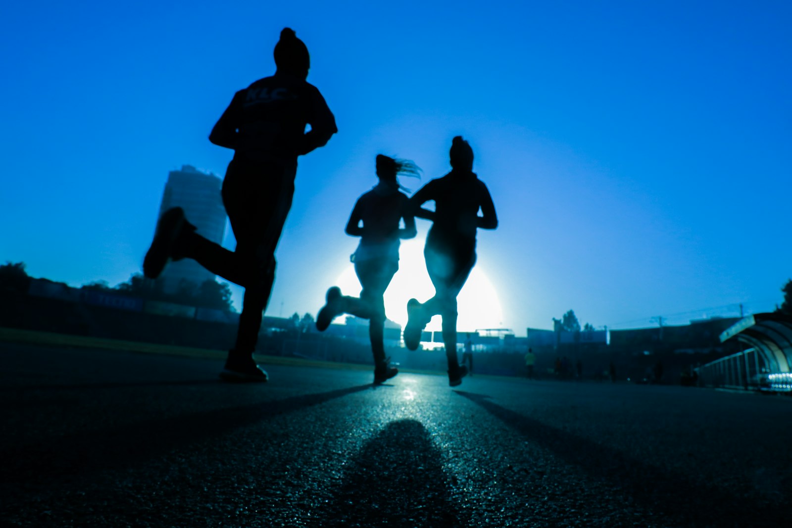 Three athletes running into a sunset